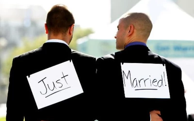 Just Married, két ember látható hátulról, mindketten fekete öltönyt viselnek. Az egyik hátán "Just"