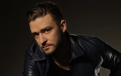 Egy férfi, Justin Timberlake, sötét bőrdzsekiben, sötét háttér előtt néz a kamerába.