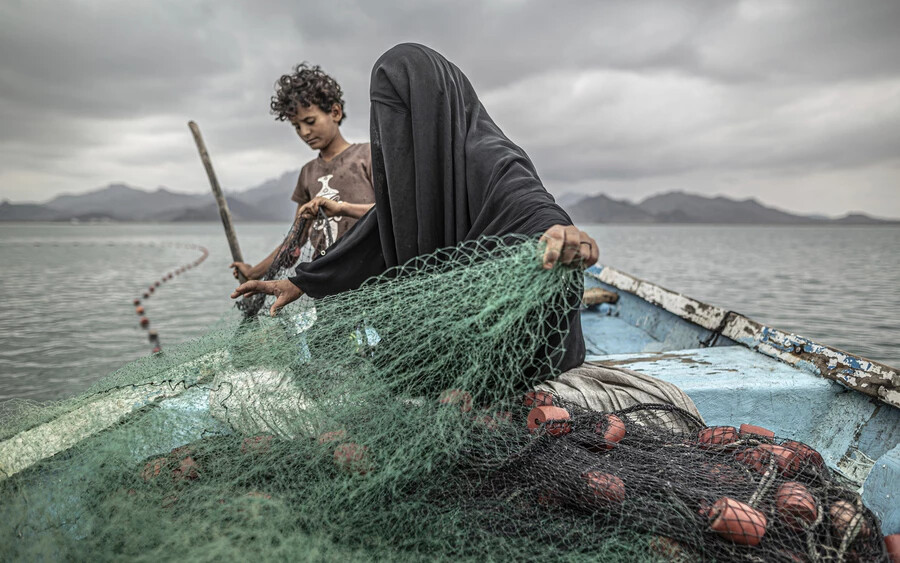Pablo Toscu Jemen Éhség, egy további háborús seb című fotója a napjaink problémái kategóriában nyert első díjat. Fatima és fia halászhálót készítenek egy hajón a jemeni Khor Omeira-öbölben. Fatimának kilenc gyermeke van, és a halászatból élnek. Bár Fatima faluját fegyveres konfliktusok pusztították, visszatért, hogy ott folytassa életét. Csónakot vásárolt a haleladásokból szerzett pénzből.