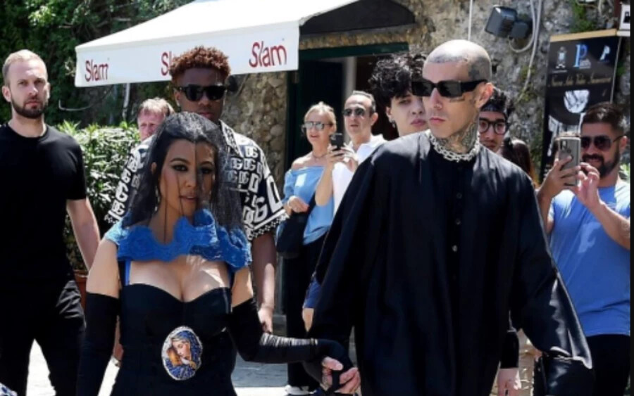 A menyasszony fekete rövid ruhát viselt, melle alatt Szűz Mária arcképével, arcát pedig fekete fátyol takarta. A vőlegény, Travis Barker egy hosszú fekete inget viselt, amely papi köntösre emlékeztet. Kim Kardashian és édesanyja, Kris Jenner is fekete ruhában érkezett a bulira. 