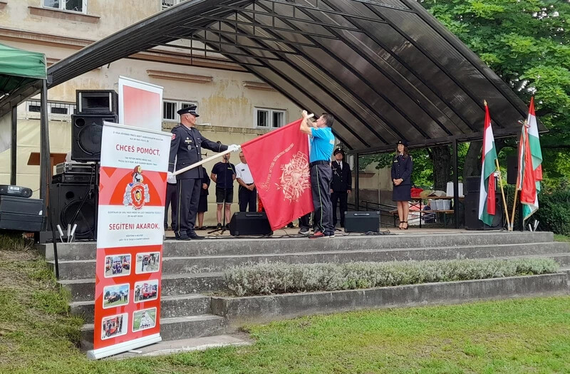 A bősi önkéntes tűzoltók képviselői ünnepi szalagot kötöttek a helyiek zászlójára (A szerző felvétele)