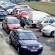 Parkoló autók Pozsonyban, szorosan egymás mellett. Egy gyalogos halad a piros autók között.