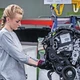 Egy nő dolgozik egy gyártósoron, szereli az alkatrészeket a géphez, háttérben a "Gyartosorjakubco"
