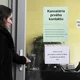 Egy nő épp belép a munkaügyi hivatal ajtaján, ahol a "Munkahivatalkassatasr" felirat látható. Az